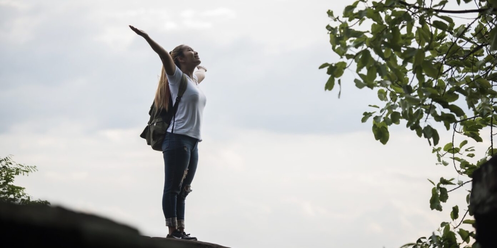 Tourist girl with arms happy with nature near the river. Travel concept.