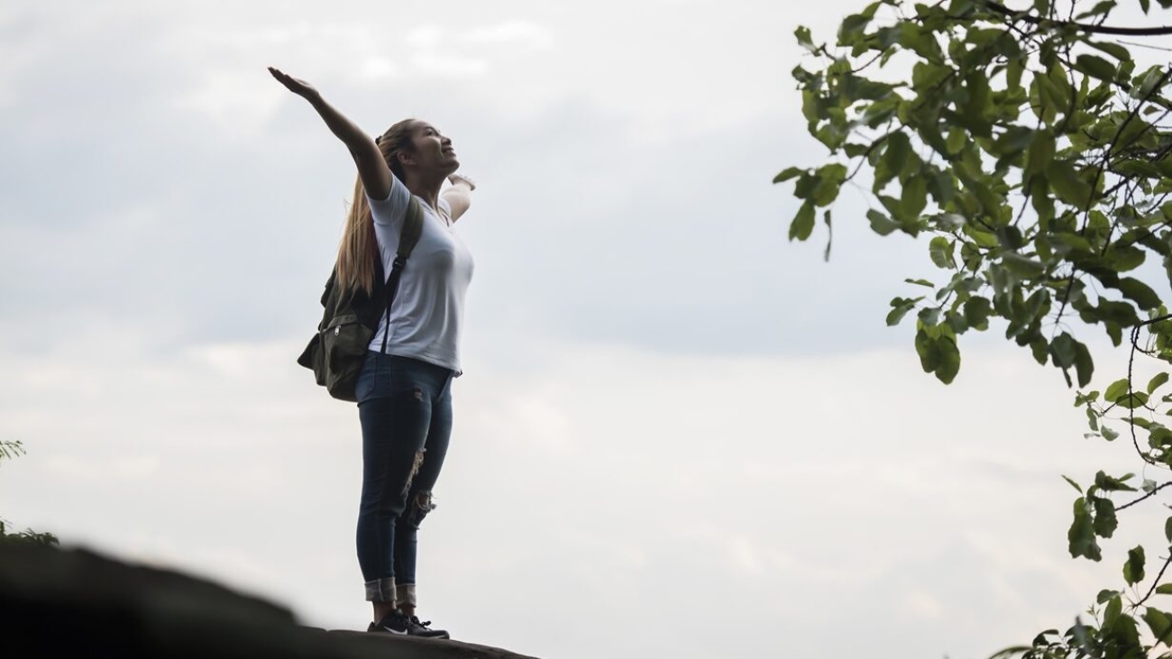 Tourist girl with arms happy with nature near the river. Travel concept.