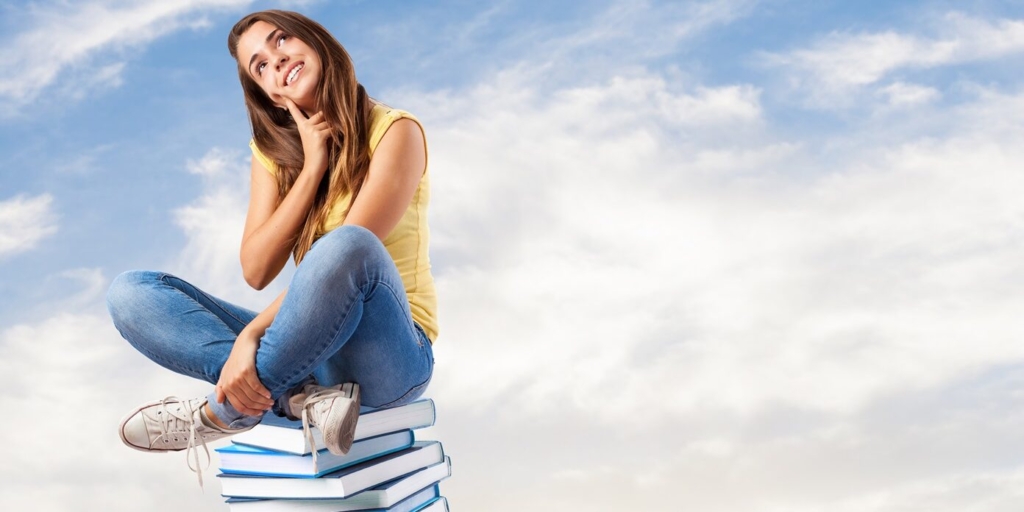 young pretty woman thinking and sitting on a big books pile