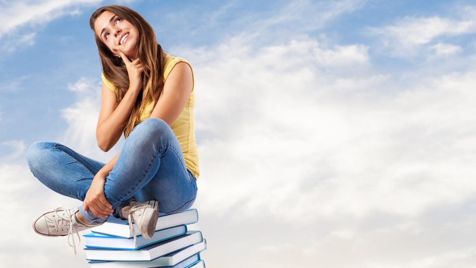 young pretty woman thinking and sitting on a big books pile