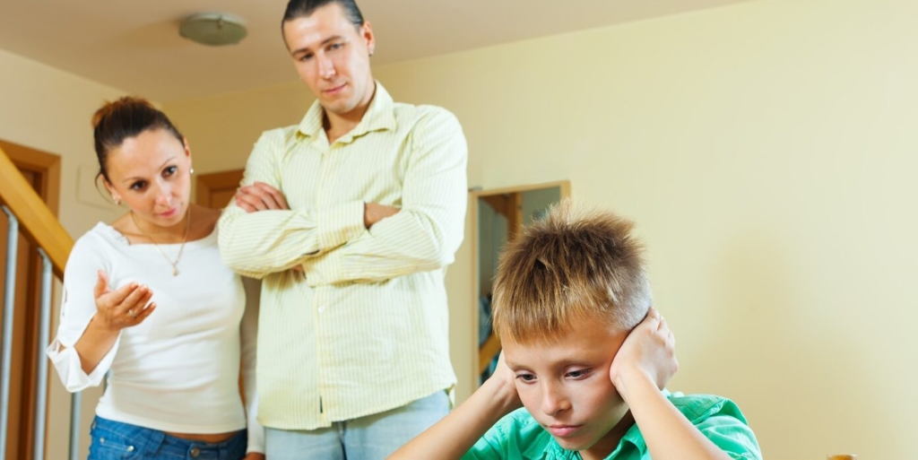 Parents berates her teenage child in interior. Focus on boy only